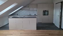 kitchen in attic with skylights, white cabinets, wooden floor, black countertop, oven, sink, faucet