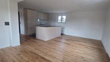 Modern kitchen with white cabinets and black granite countertop, wooden floor, and a window
