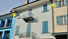 Two story house, blue and white painted walls, chimney, two balconies, windows with blue shutters
