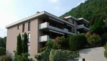 3 story building, balconies, greenery, mountain backdrop