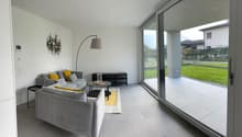 modern style living room, two grey sofas, table, decorative lamp, wall decor, sliding glass doors to balcony with a view
