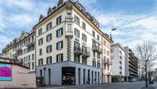 5 story building, beige and white facade, green shutters, balconies, street level shops