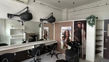 A salon space with chairs, a mirror, lamps, and a sink