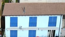 White house with blue shutters, brown roof, raised ground floor, garden