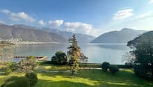 Green lawn, various trees and bushes, distant mountains, lake with a dock