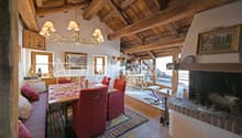 Dining area with dining table, red chairs, fireplace, wood beam ceiling, large windows, wood rocking chair, chandelier