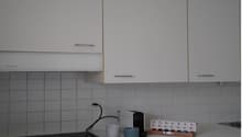 white cabinets, tiled walls, electric stove, coffee maker, coffee cups, small boxes