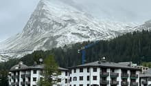 An apartment complex with 3 stories and a mountain in the background