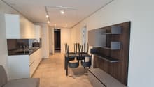 Modern kitchen with a dining area, living room with a couch, and a minimalist interior design