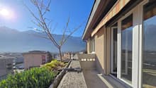 Building with balcony, plants, and a view of mountains