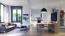 Open-concept living room and kitchen with large windows, gray sofa, wooden dining table and chairs, kitchen with white cabinets and appliances, black pendant light, and a plant decoration.