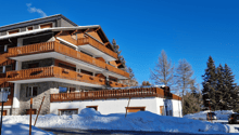 Modern multi-level building, wooden balconies, brick facade, snow-covered ground