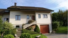 2 story house, white stucco, brown windows, brown door, stone driveway, stairs leading to wooden front door, garage