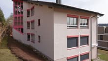 Modern apartment building with multiple windows, red trims, and a chimney on top