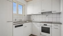 modern kitchen with a white finish, granite countertops, white cabinets, and blue ceramic tiles. A dishwasher is installed below the countertop, a sink and faucet are located above it, and an oven is positioned next to the countertop.