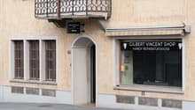 2-storey building with an arched entrance, brown wooden balcony, white awning, Gilbert Vincent shop at ground floor, and several windows