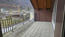 balcony with tiled floor, wooden ceiling, metal railings, view of mountains and buildings