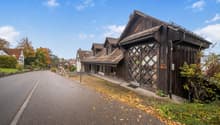 Detached house, brown wooden walls, grey roof, arched window