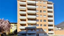 Multi-story apartment building, balconies, large windows, main entrance, exterior parking