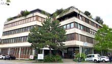 modern office building, beige exterior, brown trim, large windows, trees, cars parked in front