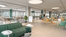 Open floor plan with breakout areas, seating areas, large windows, and office equipment.