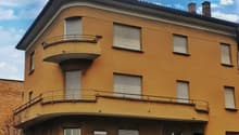 3 story building, yellow facade, chimneys, balconies, windows, door, fence, street