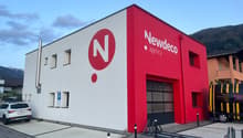 Commercial building, red and white wall, large window, 3rd floor, car parked, mountains in background