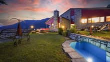 Modern house with outdoor pool, garden, mountains in background, evening lights