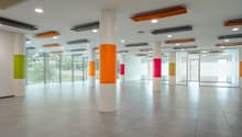 spacious room, white pillars, orange, green, and pink stripes on pillars, tiled floor, large windows, reflective surface