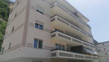 Multi-story apartment building with beige exterior, large windows, and balconies on each floor.