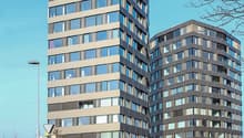 Two high-rise buildings, brown and white facades, many windows, curved architecture on the right building.