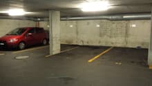 underground parking lot, concrete walls, yellow parking lines, parked red car, drain cover, pipe on wall
