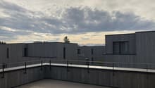 Rooftop terrace with wooden flooring, metal railings, and a view of the surrounding area