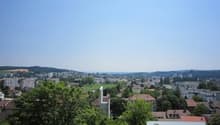 Cityscape with multiple buildings, trees, and a clear blue sky