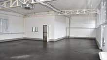 Empty room with white walls, black floor, windows, and an open door.