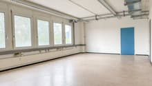 Empty room with white walls, beige floor, large windows, blue door, metal beams on ceiling