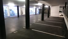 An underground parking lot, concrete floors, metal pillars, parking spots, windows