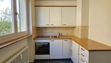 Empty kitchen, wooden countertops, white cabinets, window, radiator, gas stove, sink