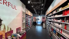 Cosmetics store with shelves full of products, sale signs, and a large wall with the word 'ERFUL'.