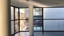 Large room, high windows, modern design, central pillar, grey floor, glass windows, reflective surfaces