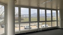 Wide windows, empty room, view of vehicles in parking area