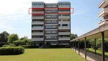Apartment building, multiple balconies, brick exterior, two floors, surrounded by a landscaped lawn