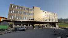 4 story building, brown exterior, multiple windows, garage, car parked in front