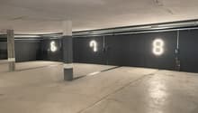 Large open parking garage with concrete floor, concrete columns, and overhead lighting
