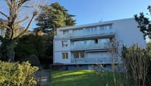 white house, several balconies, 3 floors, large windows, garden, shrubs, green grass