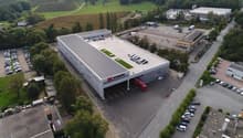 Industrial building with a car park on a landscaped plot with green spaces, located near a road
