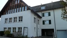 3 story house, white walls, wooden roof, multiple windows, garage