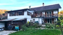 White house, brown roof, balcony, large front yard, attached wooden garage, chimney