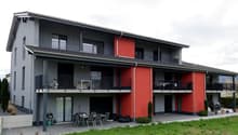 2 story house, gray and red exterior, multiple balconies, outdoor dining area, bicycles