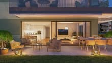terraced apartment, glass sliding doors, outdoor seating, illuminated with warm lights, lush green landscape, wooden floors, and a clear sky